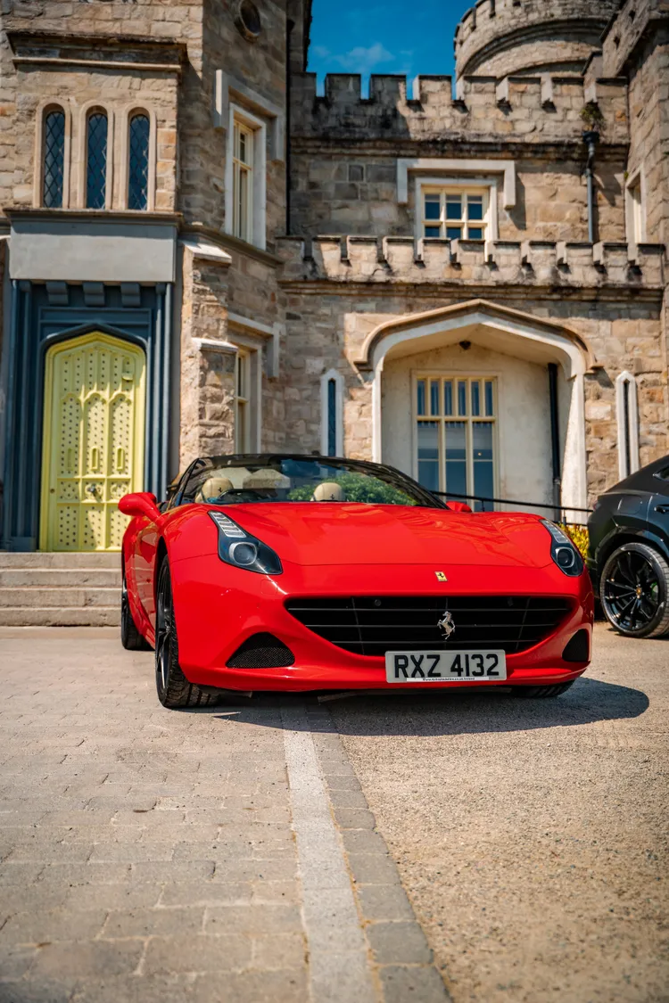 Red Ferrari California T outside a stone country house