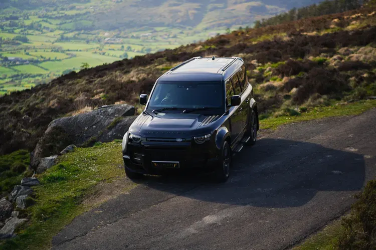 Black Land Rover Defender on a mountain road above the Irish countryside
